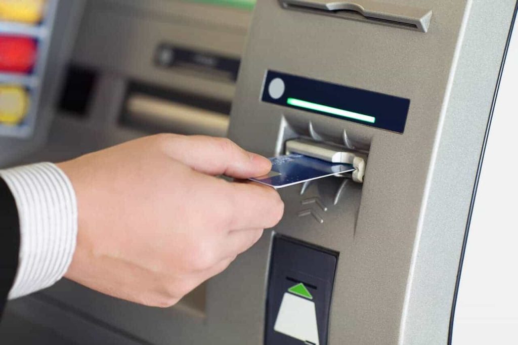 Male hand businessman inserts credit card into the ATM Taking Cash Advance